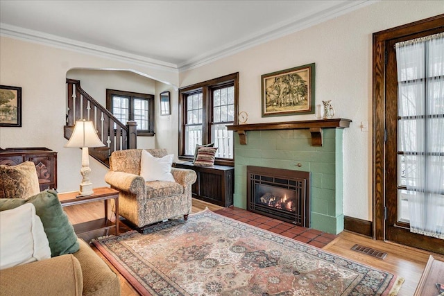 living area with visible vents, crown molding, and wood finished floors