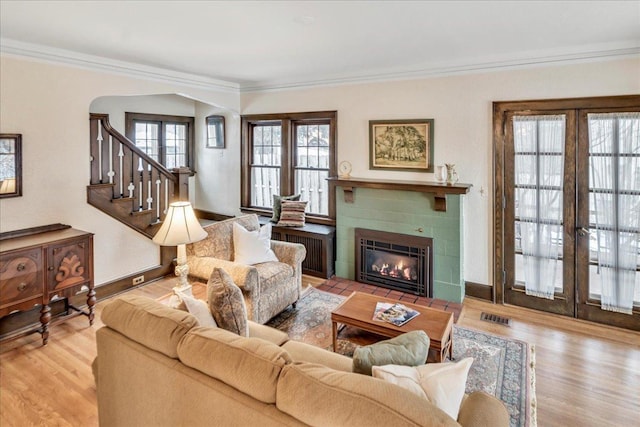 living room with a fireplace, wood finished floors, visible vents, and crown molding