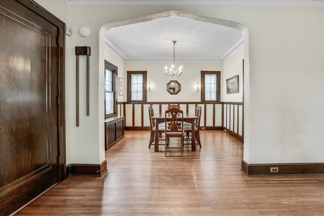 dining area featuring an inviting chandelier, plenty of natural light, crown molding, and wood finished floors