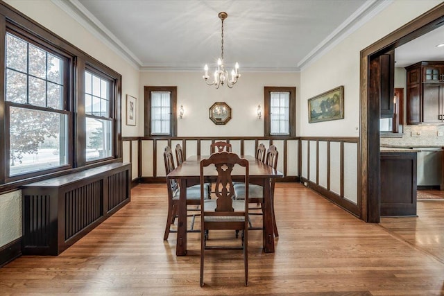 dining room with a chandelier, crown molding, baseboards, and wood finished floors