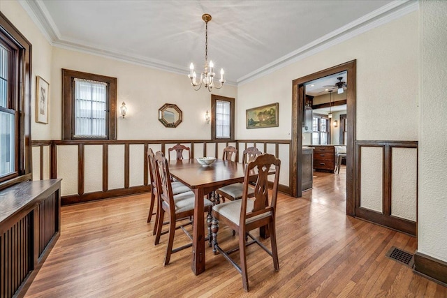 dining area with light wood-style flooring, visible vents, ornamental molding, and a notable chandelier