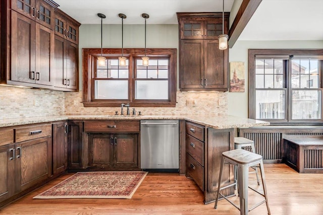 kitchen featuring backsplash, a sink, light wood-style flooring, and stainless steel dishwasher