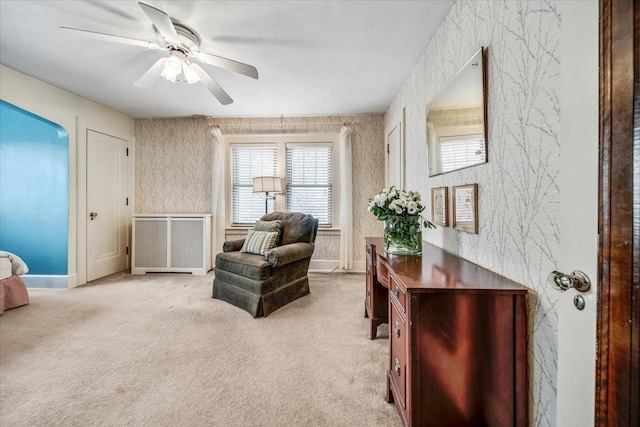 living area featuring radiator heating unit, light carpet, ceiling fan, baseboards, and wallpapered walls