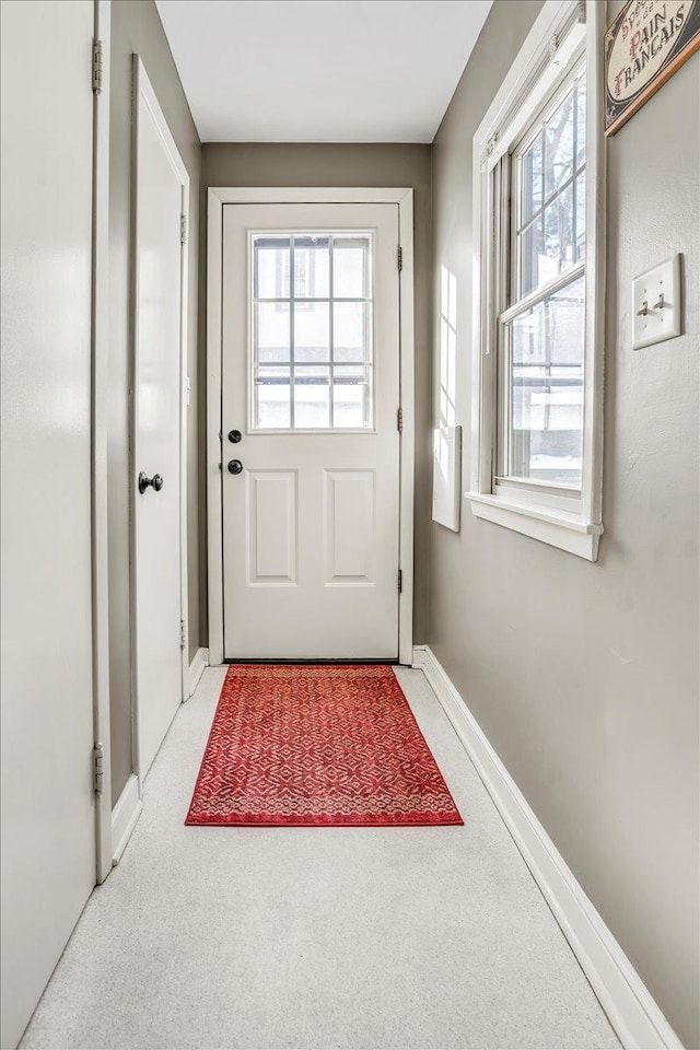 doorway to outside featuring carpet floors and baseboards