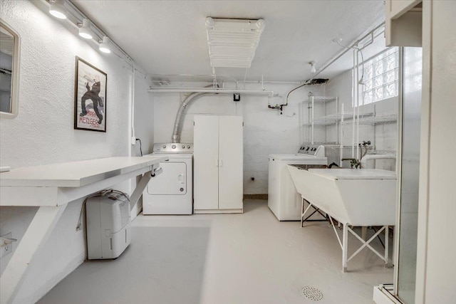 clothes washing area featuring a textured wall, independent washer and dryer, a sink, and laundry area