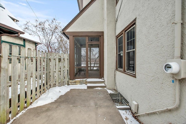 view of exterior entry with fence and stucco siding