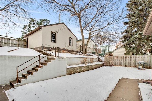 yard covered in snow featuring fence and stairway