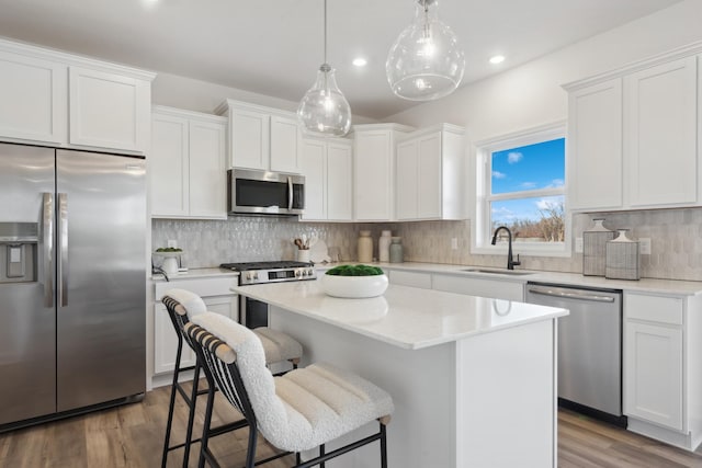 kitchen featuring stainless steel appliances, a kitchen island, white cabinetry, and sink