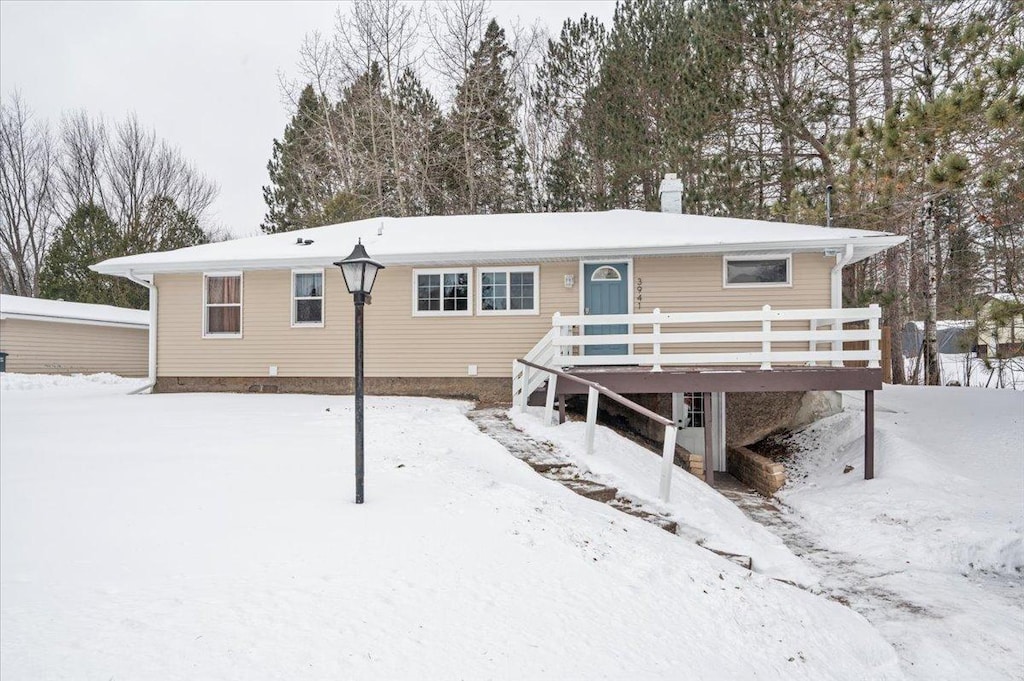 snow covered rear of property featuring a deck