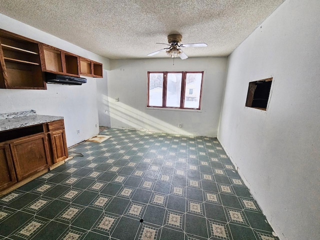 kitchen with ceiling fan, light stone countertops, and a textured ceiling