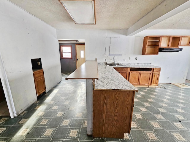 kitchen with a textured ceiling, kitchen peninsula, and sink