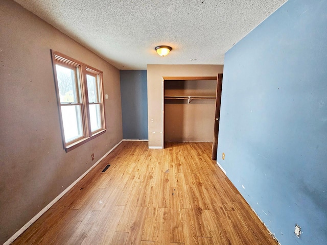 unfurnished bedroom featuring a closet, a textured ceiling, and light hardwood / wood-style flooring