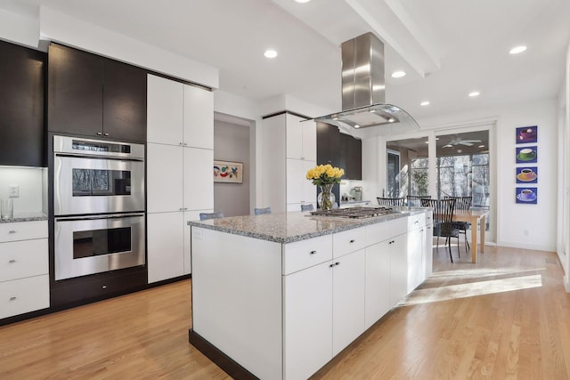 3529 Green Ridge Rd, Minnetonka, MN 55305 - kitchen with stainless steel appliances, island range hood, a center island, white cabinetry, and light stone countertops
