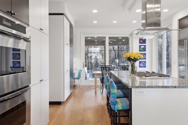 3529 Green Ridge Rd, Minnetonka, MN 55305 - kitchen with island range hood, appliances with stainless steel finishes, modern cabinets, a breakfast bar area, and recessed lighting