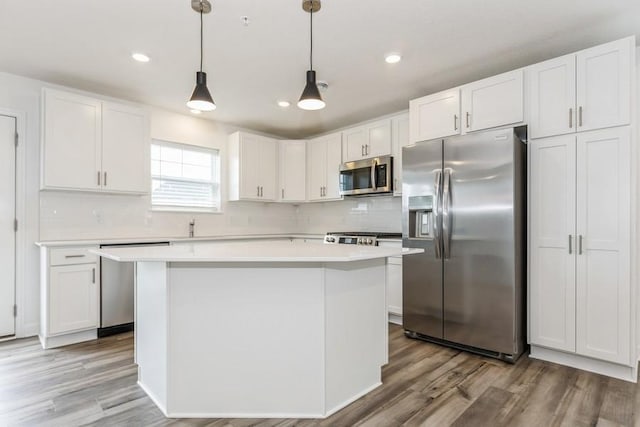 kitchen with white cabinets, backsplash, hanging light fixtures, and appliances with stainless steel finishes