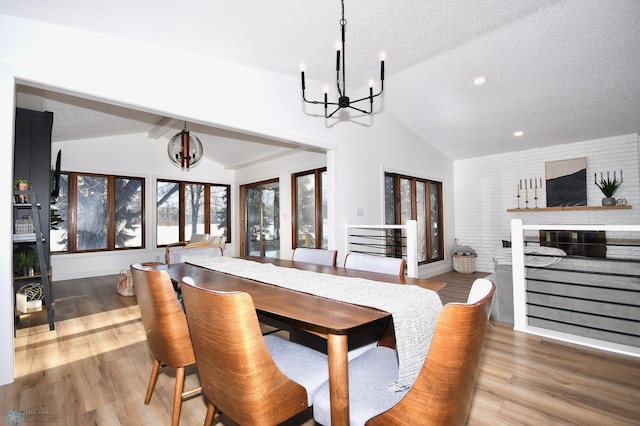 dining area featuring a fireplace, lofted ceiling with beams, a textured ceiling, and hardwood / wood-style flooring