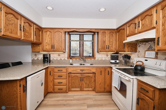 kitchen featuring a textured ceiling, white appliances, light hardwood / wood-style flooring, and sink