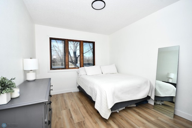 bedroom with light hardwood / wood-style floors and a textured ceiling