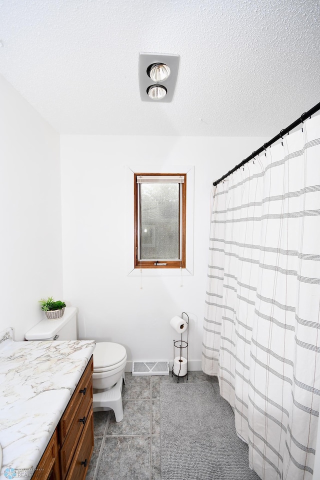 bathroom with tile patterned floors, vanity, toilet, and a textured ceiling