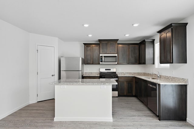 kitchen featuring a center island, light hardwood / wood-style flooring, dark brown cabinets, light stone counters, and stainless steel appliances