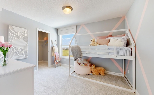 carpeted bedroom with a walk in closet, a textured ceiling, and a closet