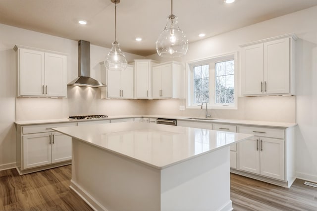 kitchen featuring white cabinetry, a center island, wall chimney exhaust hood, and pendant lighting