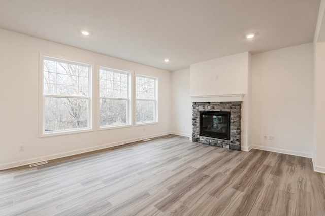 unfurnished living room with a fireplace and light hardwood / wood-style floors