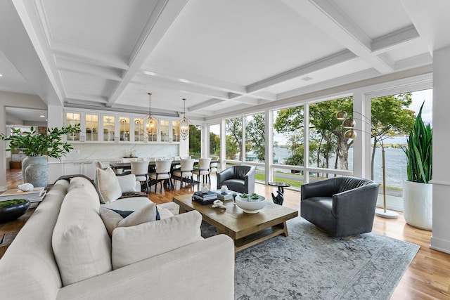 living room featuring coffered ceiling, light hardwood / wood-style flooring, beamed ceiling, and a water view