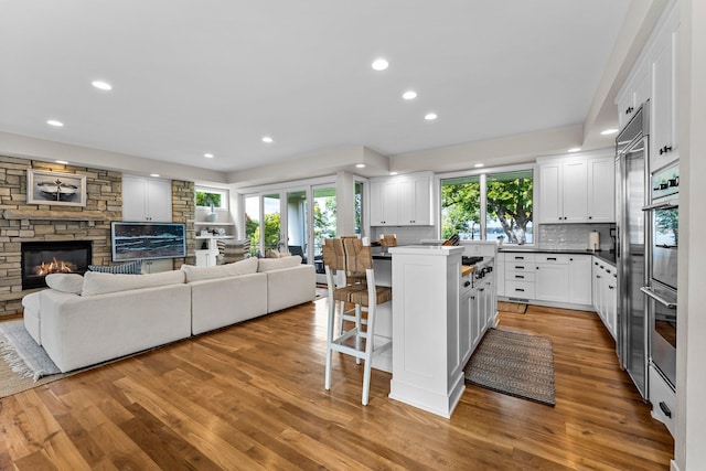 kitchen with white cabinetry, backsplash, a kitchen breakfast bar, light hardwood / wood-style floors, and a kitchen island