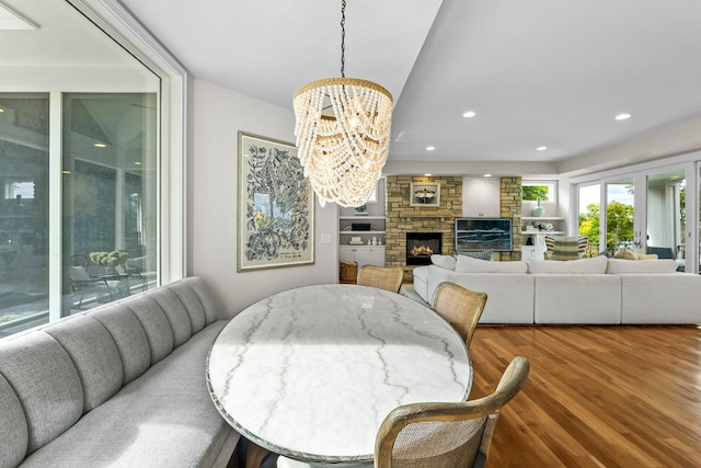 dining room featuring hardwood / wood-style flooring, a fireplace, and a notable chandelier