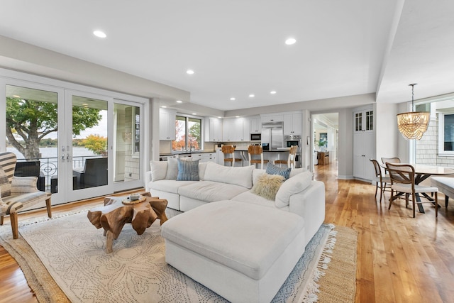 living room featuring sink, a chandelier, light hardwood / wood-style floors, and french doors