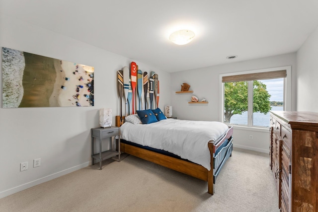 bedroom featuring a water view and light colored carpet