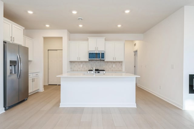 kitchen featuring backsplash, white cabinetry, a kitchen island with sink, and appliances with stainless steel finishes