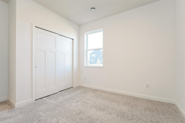 unfurnished bedroom with light colored carpet and a closet