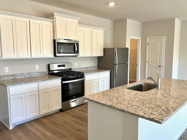 kitchen featuring sink, stainless steel appliances, light stone counters, a kitchen island with sink, and white cabinets