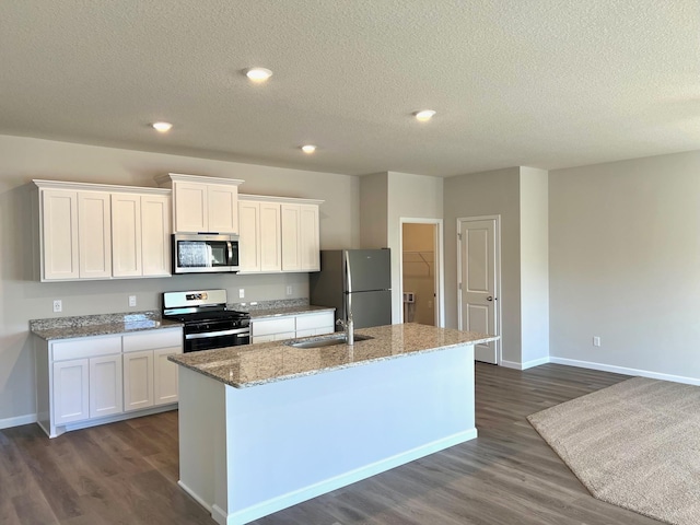 kitchen featuring a center island with sink, white cabinets, a textured ceiling, and appliances with stainless steel finishes