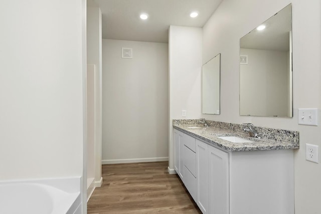 bathroom featuring a bath, wood-type flooring, and vanity