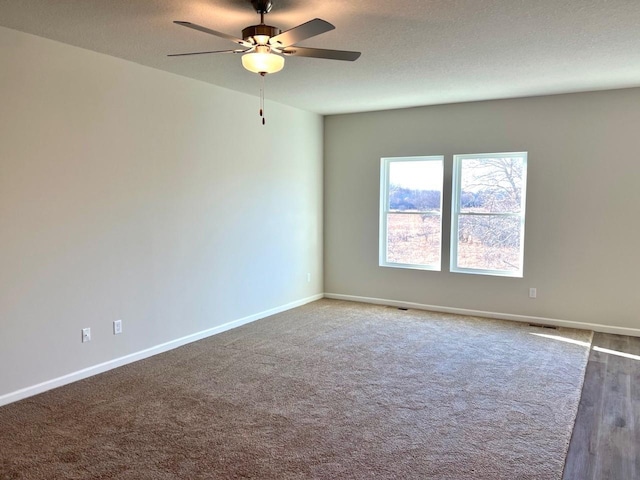 carpeted spare room featuring ceiling fan and a textured ceiling