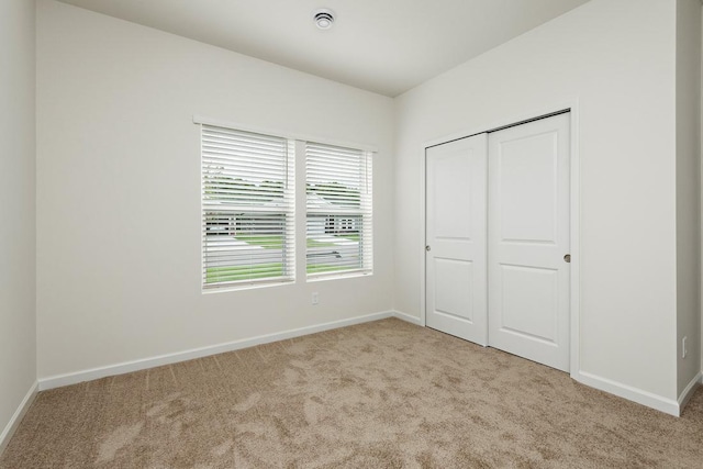 unfurnished bedroom featuring light carpet and a closet