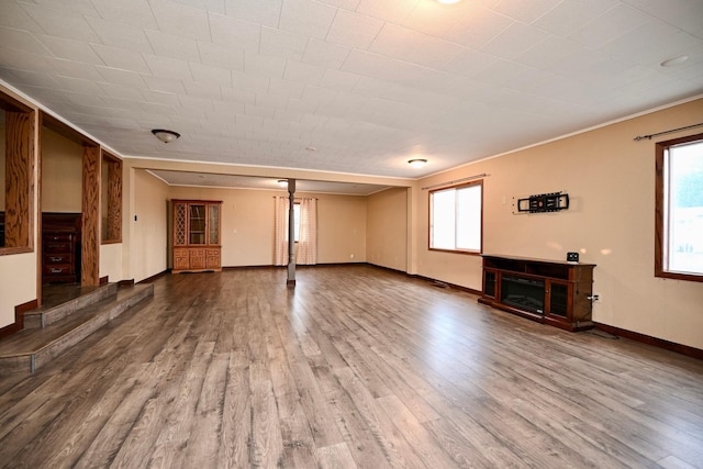 unfurnished living room featuring hardwood / wood-style flooring and crown molding