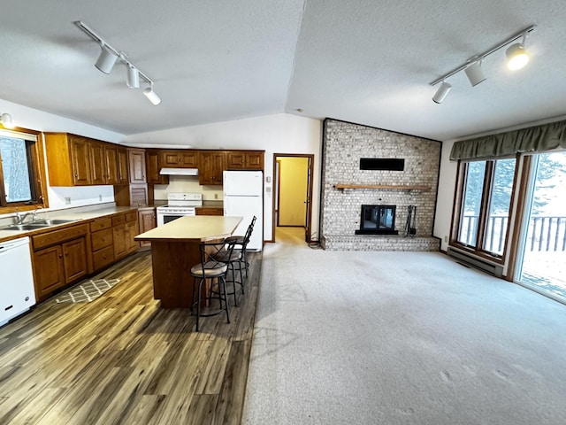 kitchen featuring sink, a center island, a fireplace, white appliances, and a kitchen breakfast bar