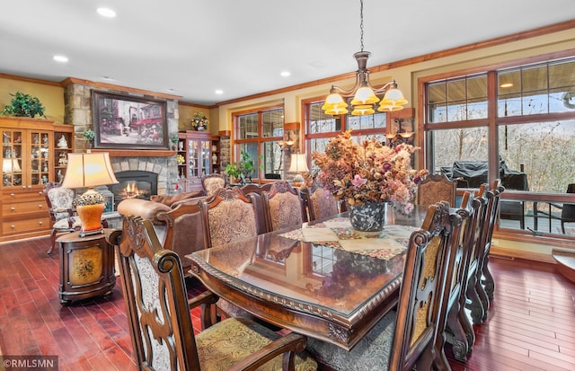 dining space with a fireplace, a chandelier, ornamental molding, and dark hardwood / wood-style floors