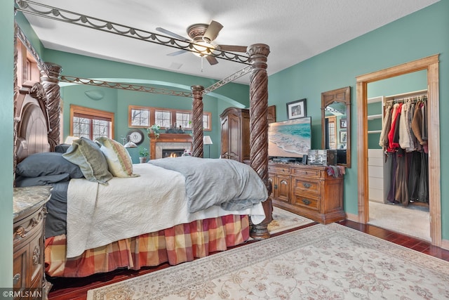 bedroom featuring a textured ceiling, hardwood / wood-style floors, ceiling fan, a closet, and a walk in closet