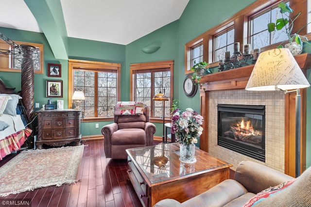 living area featuring a tiled fireplace and dark wood-type flooring