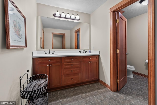 bathroom featuring a textured ceiling, vanity, and toilet