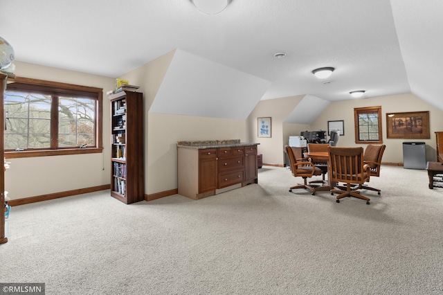 office area featuring light colored carpet, vaulted ceiling, and a wealth of natural light