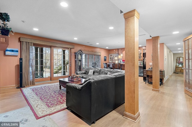 living room with decorative columns and light hardwood / wood-style floors