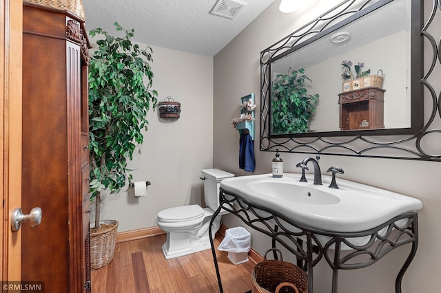 bathroom featuring toilet, a textured ceiling, and hardwood / wood-style floors