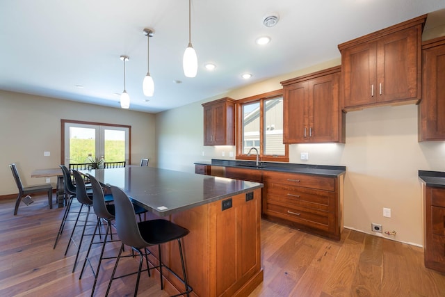 1018 Mahoe Way, Mankato, MN 56001 - kitchen with dark countertops, brown cabinets, a center island, wood finished floors, and recessed lighting