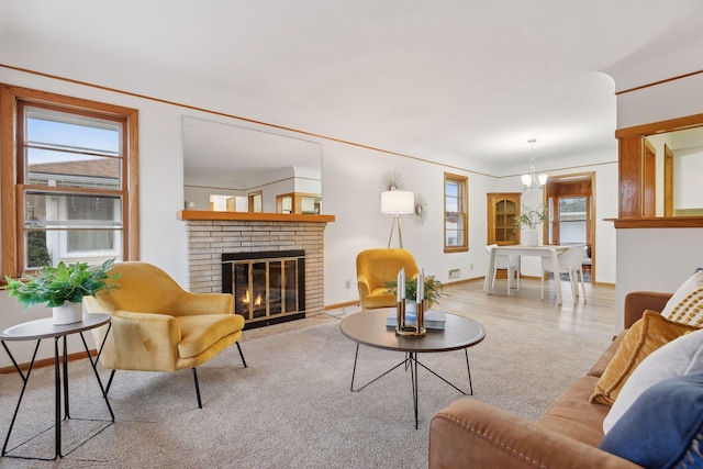 carpeted living room with a brick fireplace, plenty of natural light, and a notable chandelier